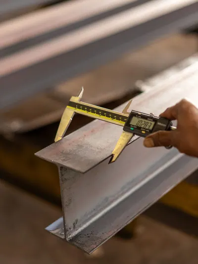 Digital caliper measuring the edge of a steel beam.