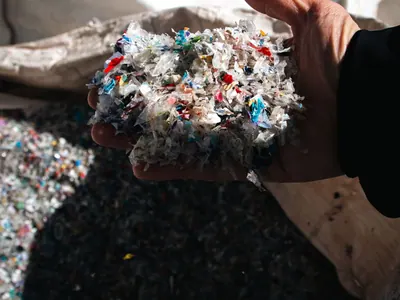 Hand holding recycled plastic granules over a bulk bag.